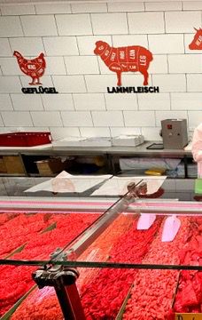 Die Fleischtheke von SILA Market mit Schildern für Geflügel und Lammfleisch an der gefliesten Wand.